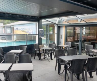 Terrasse couverte avec tables et chaises au Camping Abijune d’Étretat