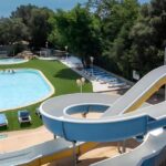 Piscine extérieure avec toboggan et transats au Camping Acqua E Sole