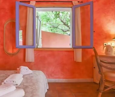 Chambre avec lit serviettes pliées et fenêtre ouverte donnant sur le jardin du Camping Acqua E Sole