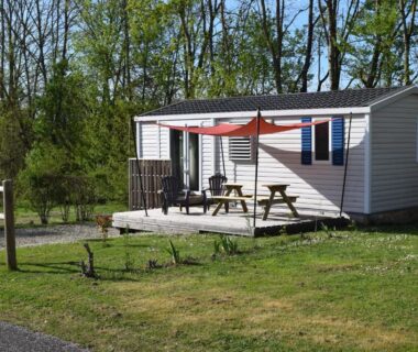 Terrasse de mobil-home avec parasol et table sur gazon au Camping Adults Only La Croix Badeau