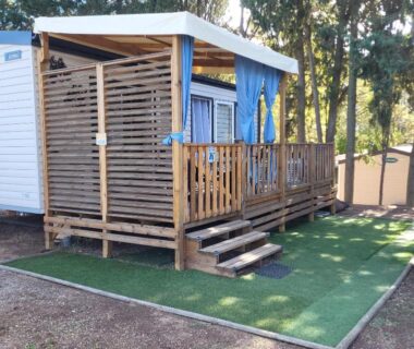 Terrasse en bois avec escalier et rideaux du Camping Agde Mobil home 4 places climatisé