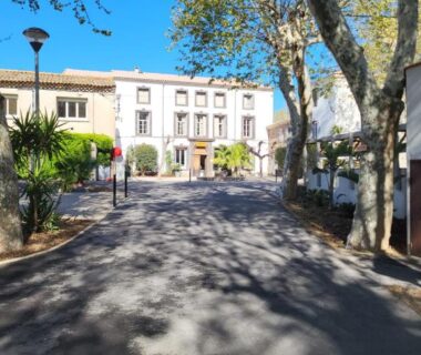 Allée ombragée bordée d'arbres devant bâtiments au Camping Agde Mobil home 4 places climatisé