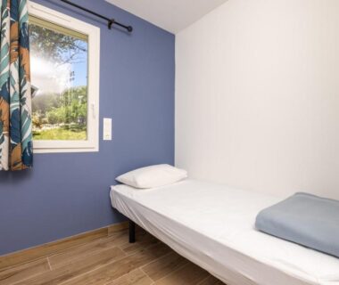 Chambre avec lit simple et fenêtre donnant sur l'extérieur au Camping Alpes Dauphiné
