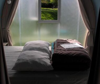 Intérieur de tente avec deux lits et fenêtre sur jardin au Camping Au Coeur de Vendome
