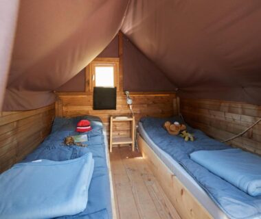 Intérieur de tente avec deux lits en bois au Camping Au Soir D’été