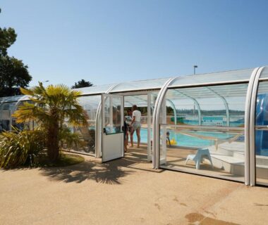 Piscine couverte sous abri transparent et palmier au Camping Au Soir D'été