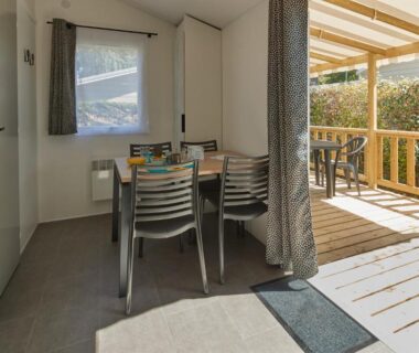 Intérieur coin repas ouvert sur terrasse en bois du Camping Au Soir D'été