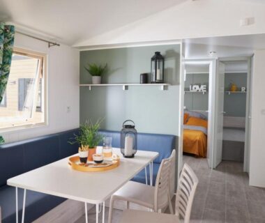 Intérieur de mobil-home avec coin repas et chambre au camping Les Foulons