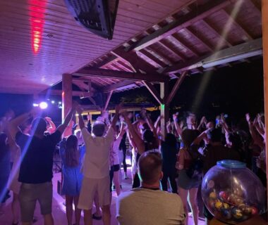 Soirée nocturne sous abri en bois avec foule dansante au Camping Les Foulons