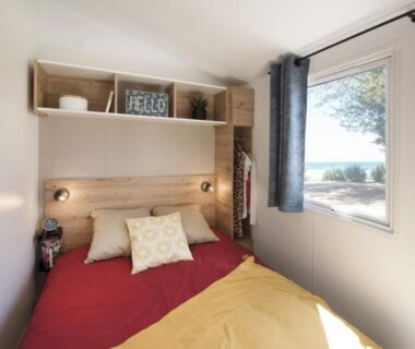Chambre avec lit double et fenêtre donnant sur la mer au Camping Bel Air
