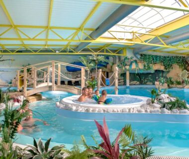 Piscine couverte tropicale avec bassin central et ponton au Camping Bel Air