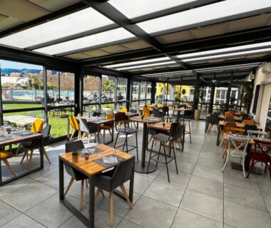Terrasse couverte avec tables dressées et chaises au Camping Bel Air