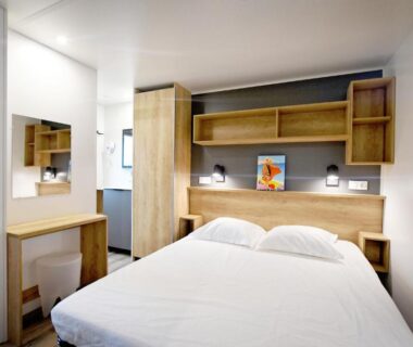 Chambre double avec lit rangements et coin bureau au Camping Bella Vista