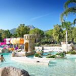 Piscine lagon avec toboggans palmiers et rochers au Camping Bella Vista