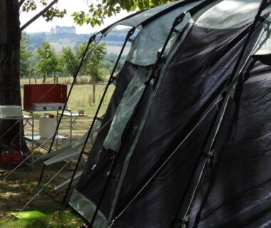 Emplacement herbeux avec tente et chaises au Camping Belle Vue