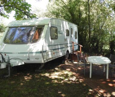 Emplacement ombragé avec caravane et terrasse en bois au Camping Belle Vue