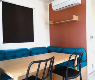 Coin repas avec banquette table chaises et climatisation au Camping Bleu Marine