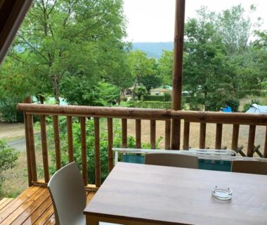 Terrasse couverte avec table et chaises et vue sur la verdure au Camping Calme et Nature Iserand