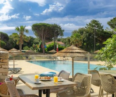 Terrasse au bord de la piscine avec tables et parasols au Camping Campo Di Liccia