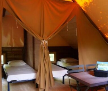 Intérieur de lodge toilé avec lits et table au Camping Canal de Berry