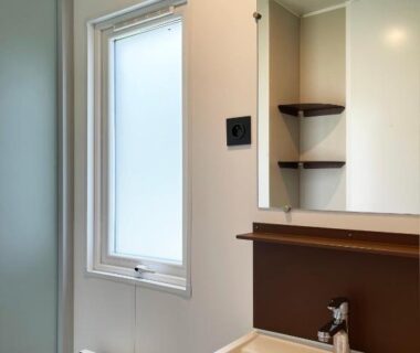 Salle de bain avec lavabo miroir et fenêtre au Camping Canal de Berry