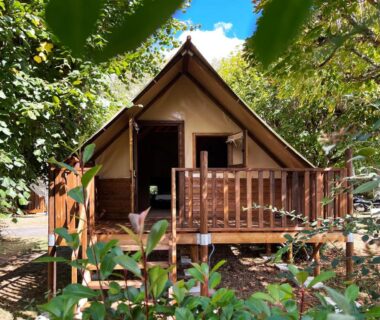 Terrasse en bois d'une tente lodge sous les arbres au Camping Canal de Berry