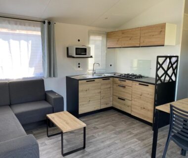 Intérieur avec coin salon canapé et kitchenette du Camping-Caravaning de la Mollière