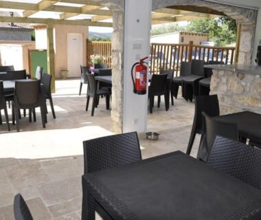 Terrasse couverte avec tables et chaises au Camping Chalets Les Chênes Verts