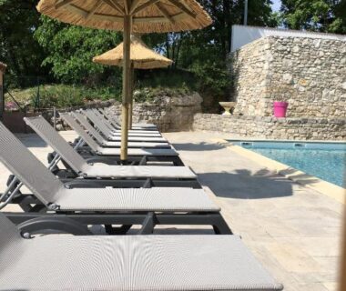 Bord de piscine avec transats et parasols au Camping Chalets Les Chênes Verts