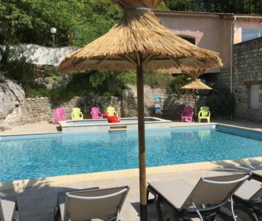 Piscine extérieure avec parasols en paille et transats au Camping Chalets Les Chênes Verts