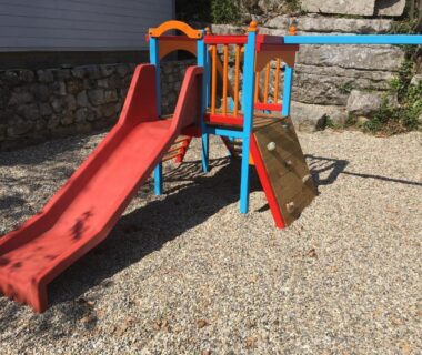 Aire de jeux avec toboggan sur sol gravier du Camping Chalets Les Chênes Verts