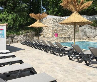 Bord de piscine avec transats et parasols en paille au Camping Chalets Les Chênes Verts