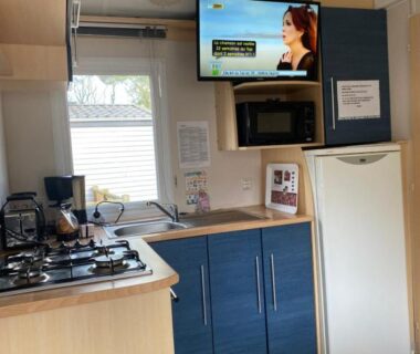 Coin cuisine avec réfrigérateur plaque de cuisson et télévision dans le mobil home du Camping Cœur De Vendée