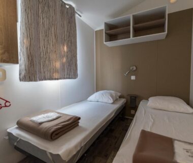 Petite chambre avec deux lits et serviettes au Camping Corsica Paradise