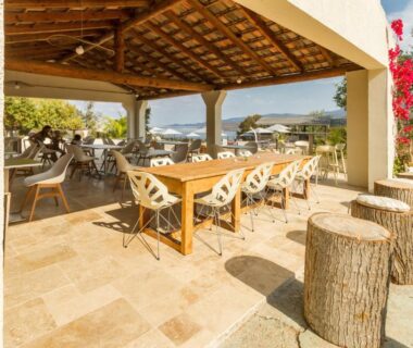 Terrasse couverte avec tables et chaises et vue sur la mer au Camping Corsica Paradise