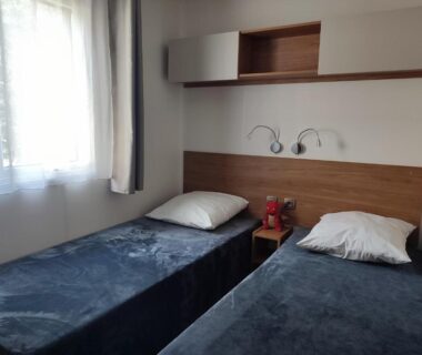Chambre avec deux lits simples et fenêtre dans le mobil-home du Camping DEL MAR