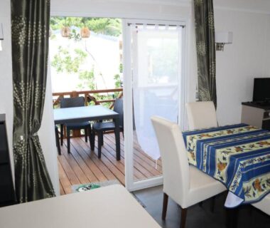 Séjour avec table et baie vitrée vers terrasse du Mobile Home O'Hara Supérieur 1060