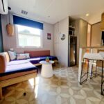 Coin salon lumineux avec canapé et cuisine ouverte du Mobile Home Excellence Camping Del Mar 52