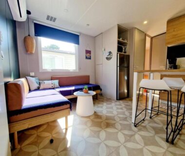 Coin salon lumineux avec canapé et cuisine ouverte du Mobile Home Excellence Camping Del Mar 52