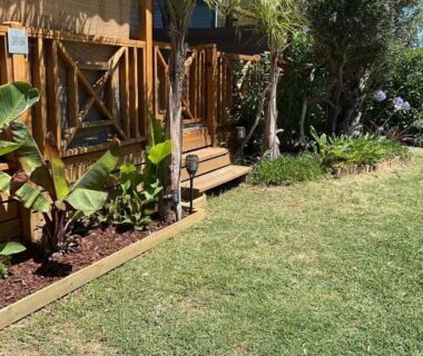Terrasse en bois avec pelouse et palmiers au mobile home Camping Del Mar B06