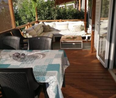 Terrasse couverte avec salon et table dans le mobil home O'Hara résidentiel B07 Camping Del Mar Village