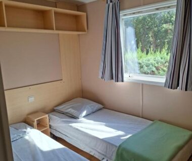 Chambre avec deux lits simples et fenêtre au Camping Des Mimosas