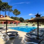 Piscine extérieure entourée de parasols et transats au Camping Des Mimosas