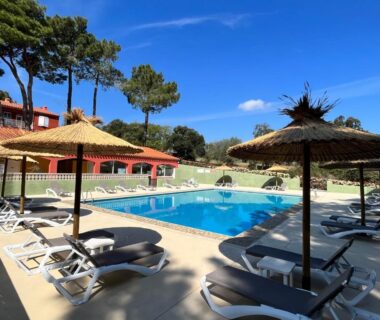 Piscine extérieure entourée de parasols et transats au Camping Des Mimosas