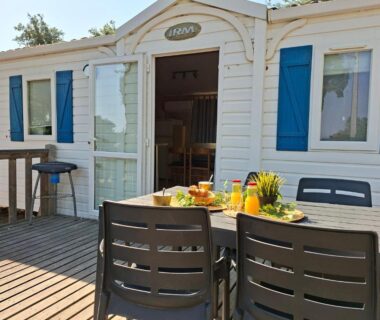Terrasse en bois avec table et chaises ensoleillées au camping Des Mimosas