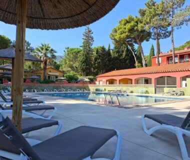 Bord de piscine avec transats et parasols au Camping Des Mimosas