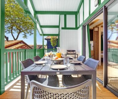 Terrasse couverte avec table de repas et jus surplombant chalets au Camping Domaine Berrua Maeva Sélection