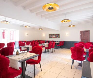 Salle de restaurant avec fauteuils rouges au Camping Domaine Berrua - Maeva Sélection