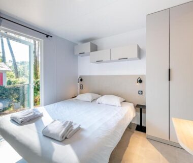 Chambre double lumineuse avec lit et fenêtre donnant sur jardin au Camping Domaine Les Oréades Maeva Sélection