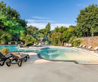 Piscine extérieure avec transats et végétation au Camping Domaine Les Oréades Maeva Sélection